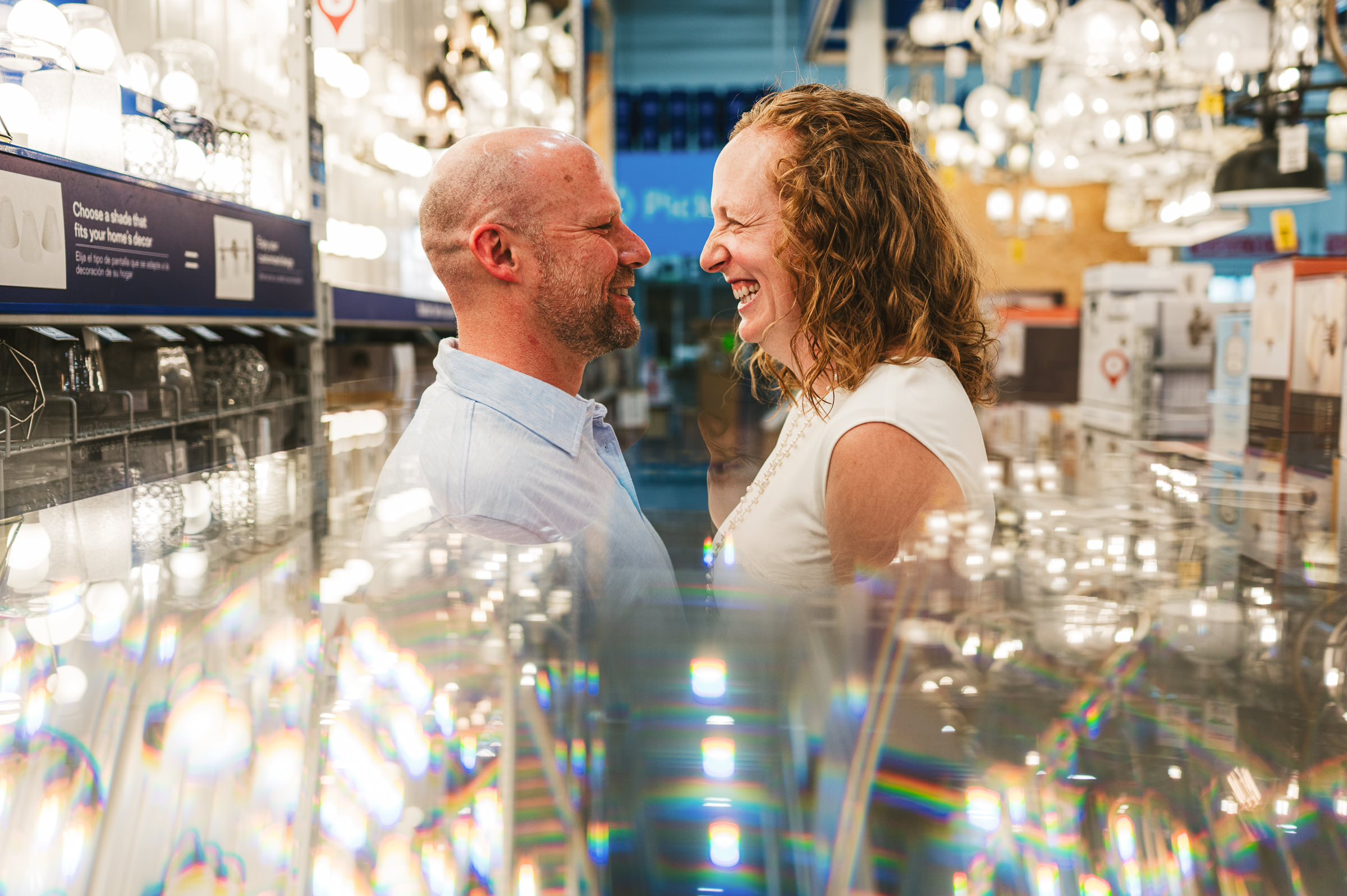 couple looking at each other in lighting aisle Westley Leon Studios Wedding Photographer Lowe's Home Improvement in Mishawaka Indiana
